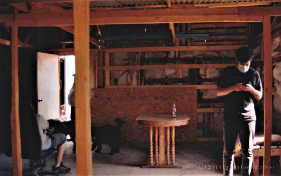 Interior of Cootramap’s 2022 self-built headquarters in La Pintana, with exposed wooden beams, unfinished partitions, a small table, and cooperative workers inside